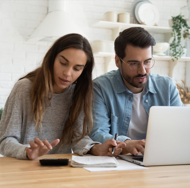 Image showing a couple at a table with a laptop and a calculator, making plans