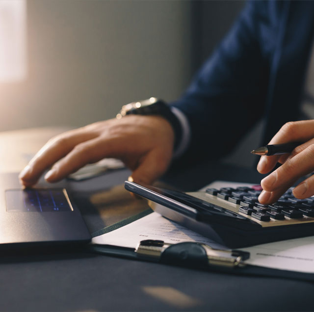 Image showing a close up of a man hands using a calculator and a laptop